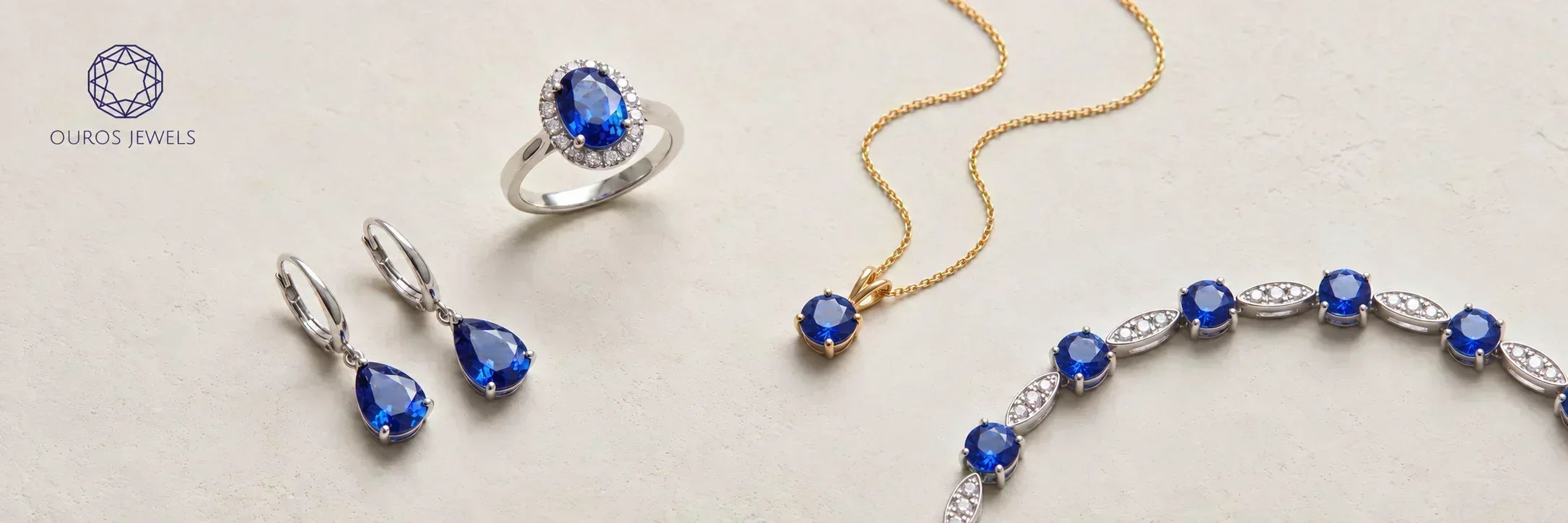 Blue sapphire jewelry collection featuring a sapphire ring, drop earrings, pendant necklace and diamond bracelet by Ouros Jewels