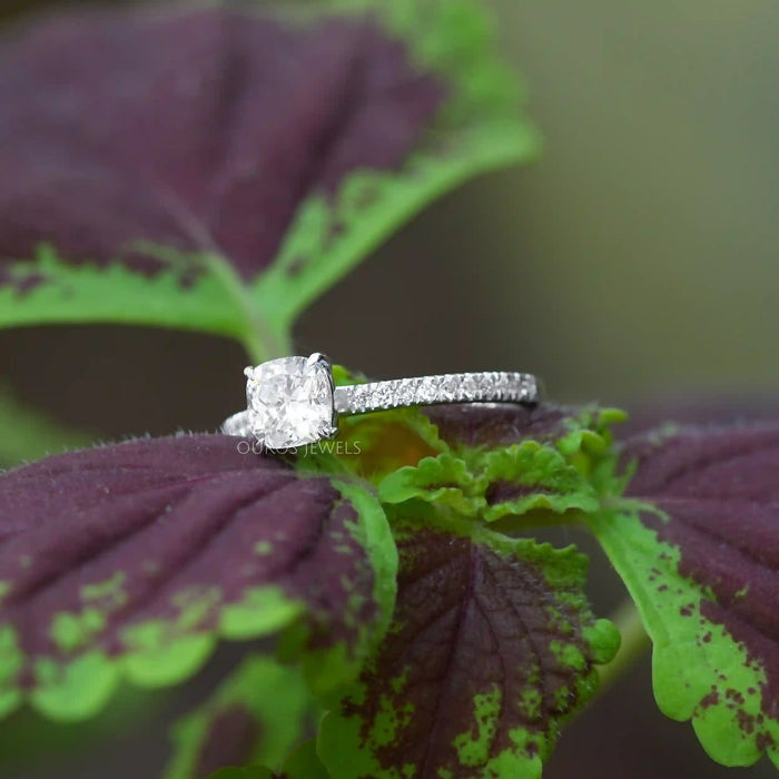 [ a cushion cut solitaire diamond ring laying on a leaf]-[Ouros Jewels]