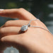[a woman's hand holding a Round necklace with a halo diamond pendant]-[Ouros Jewels]