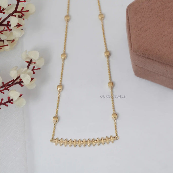 Zigzag Chain Necklace on White Background with flower and box display on white surface.