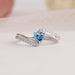 Close up view of bypass set blue heart shaped engagement ring in 14k white gold.