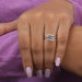 In finger front view of bypass set blue pear shaped engagement ring crafted with 14k white gold.