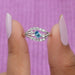 Two finger front view of pear shaped bypass diamond engagement ring in 14k white gold.