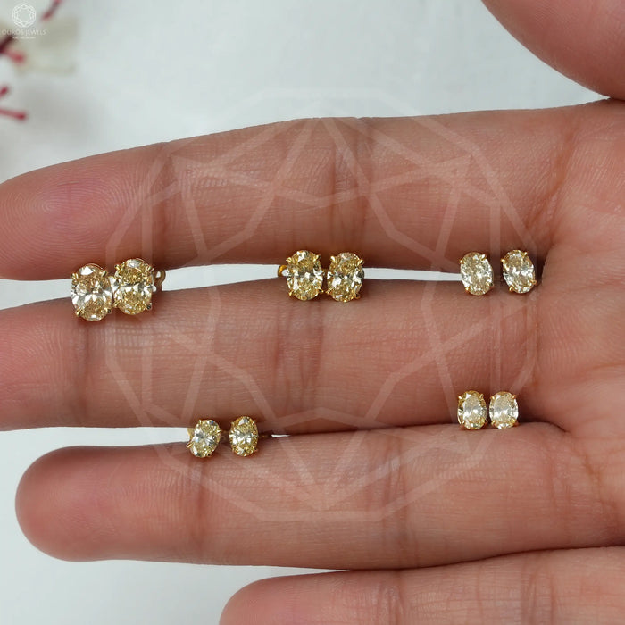 Different sizes of yellow oval shape diamond studs with claw prongs