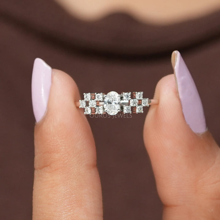 In two finger front view of oval cut cluster diamond ring made of VS clarity.