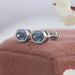 14k white gold stud earrings main stones blue oval shaped set in bezel.