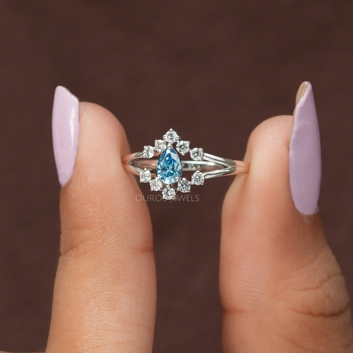 A close up look of exquisite blue pear lab made diamond ring with halo of round diamonds