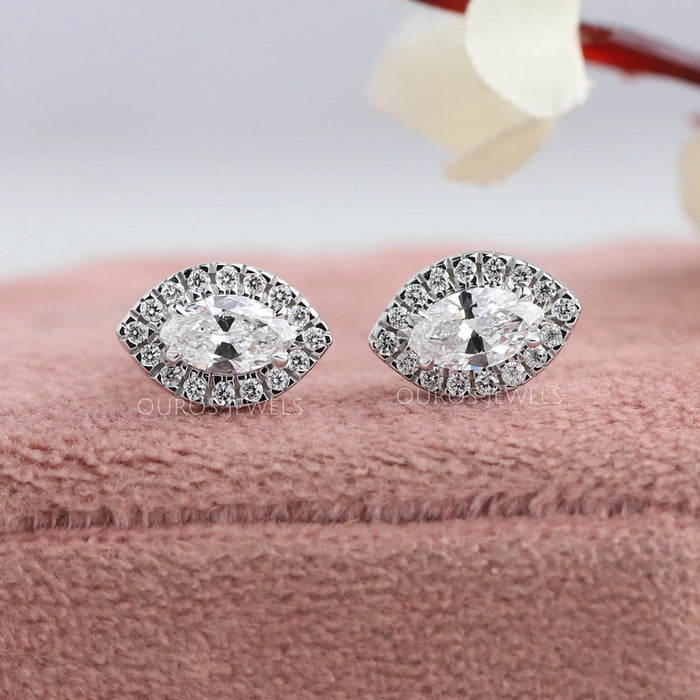 A stunning pair of marquise diamond solitaire stud earrings with halo of round brilliant cut diamonds