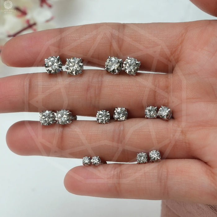 In hand view of solitaire earrings with round cut diamonds in olive color