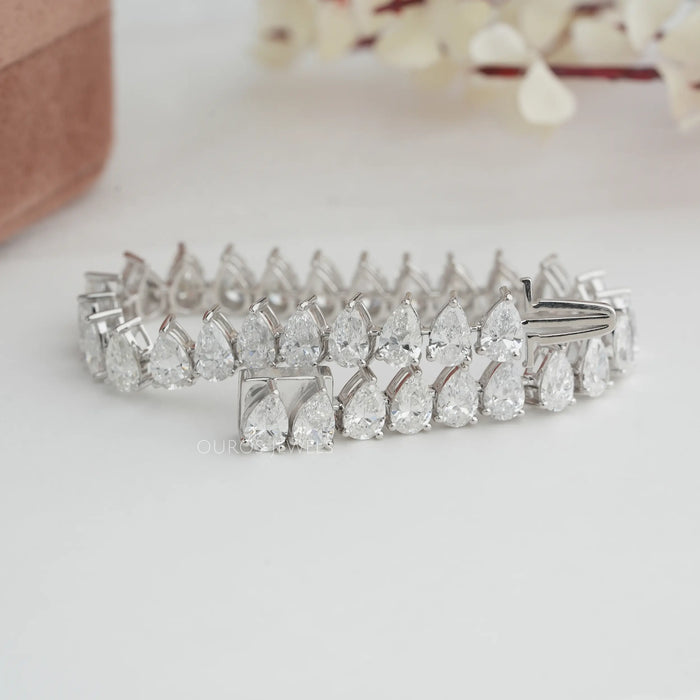 Framed from 14K white gold and adorned with a stunning  colorless pear-shaped lab created tennis bracelet diamond.