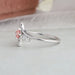Round accent stones studded on white gold curved shank of pink princess engagement ring