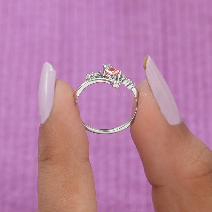 A close up look of curved band featuring a pink princess cut diamond made in white gold