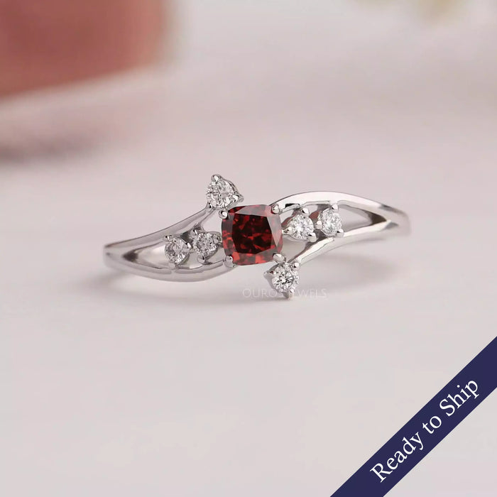 Red cushion cut cluster diamond ring made of 4k white gold with round cut diamonds.