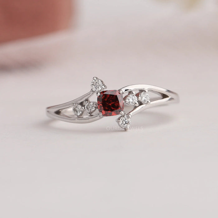Front view of cluster diamond ring set in red cushion shape with side round diamonds. Crafted with 14k white gold.