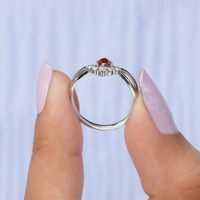 Two finger view of red oval diamond infinity ring with crafted  side round small diamonds.