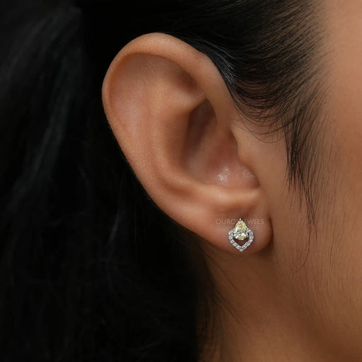 In ear look of yellow pear shaped lab created diamond studs with brilliant halo of round diamonds